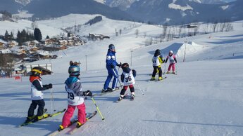 Skischule Edelweiß Skilehrer auf der Piste mit Kindern mit Startnummern | © Skischule Edelweiß