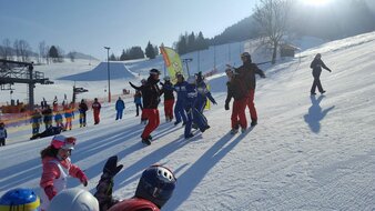 Tanzende Skilehrer vor einer Skikurs-Kindergruppe | © Skischule Edelweiß