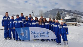 Skischule Edelweiß Skilehrer Gruppenfoto mit Skischulen Beach-Flag | © Skischule Edelweiß