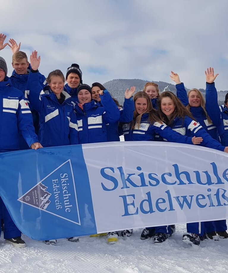 Skischule Edelweiß Skilehrer Gruppenfoto im Schnee mit Skischul-Fahne | © Skischule Edelweiß